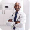 Male doctor smiling with arms crossed in a hospital hallway.